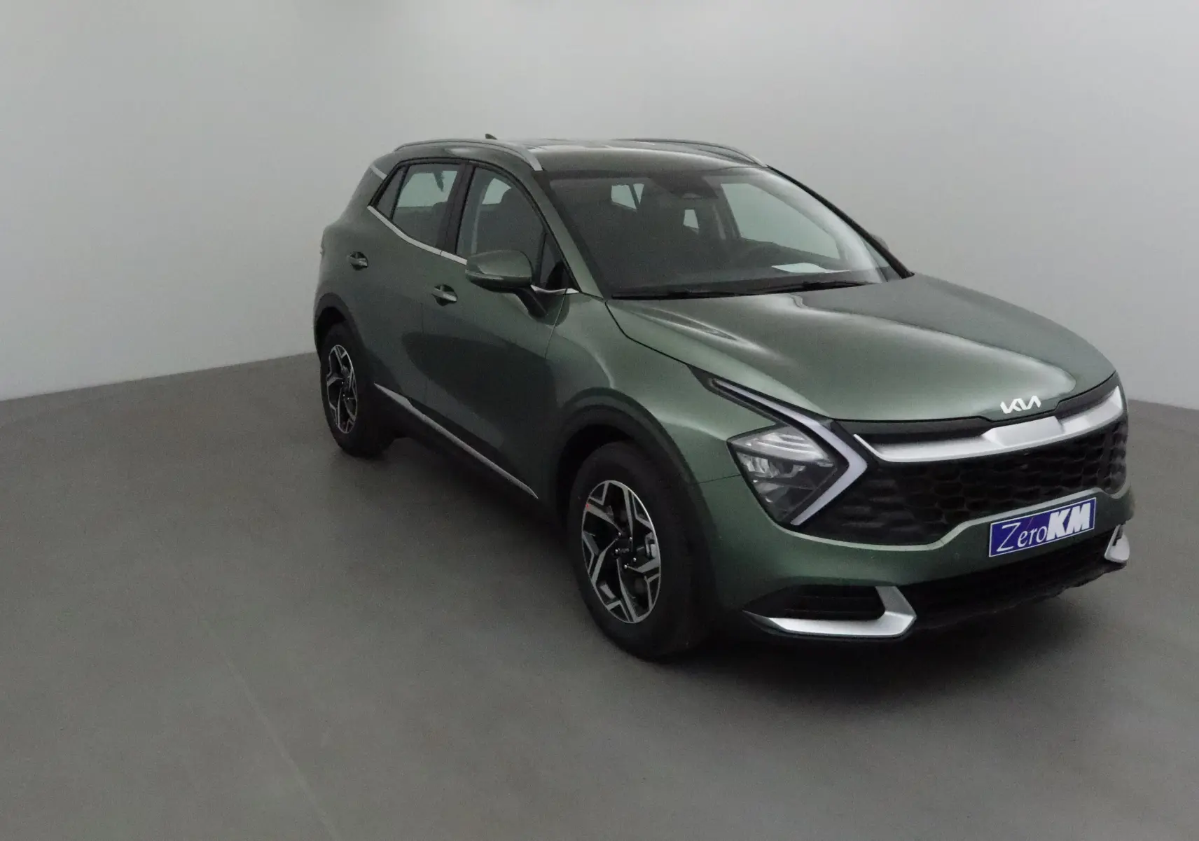 KIA SPORTAGE vert Borneo en 3/4 avant droit, avec calandre noire et signature lumineuse en V distinctive.