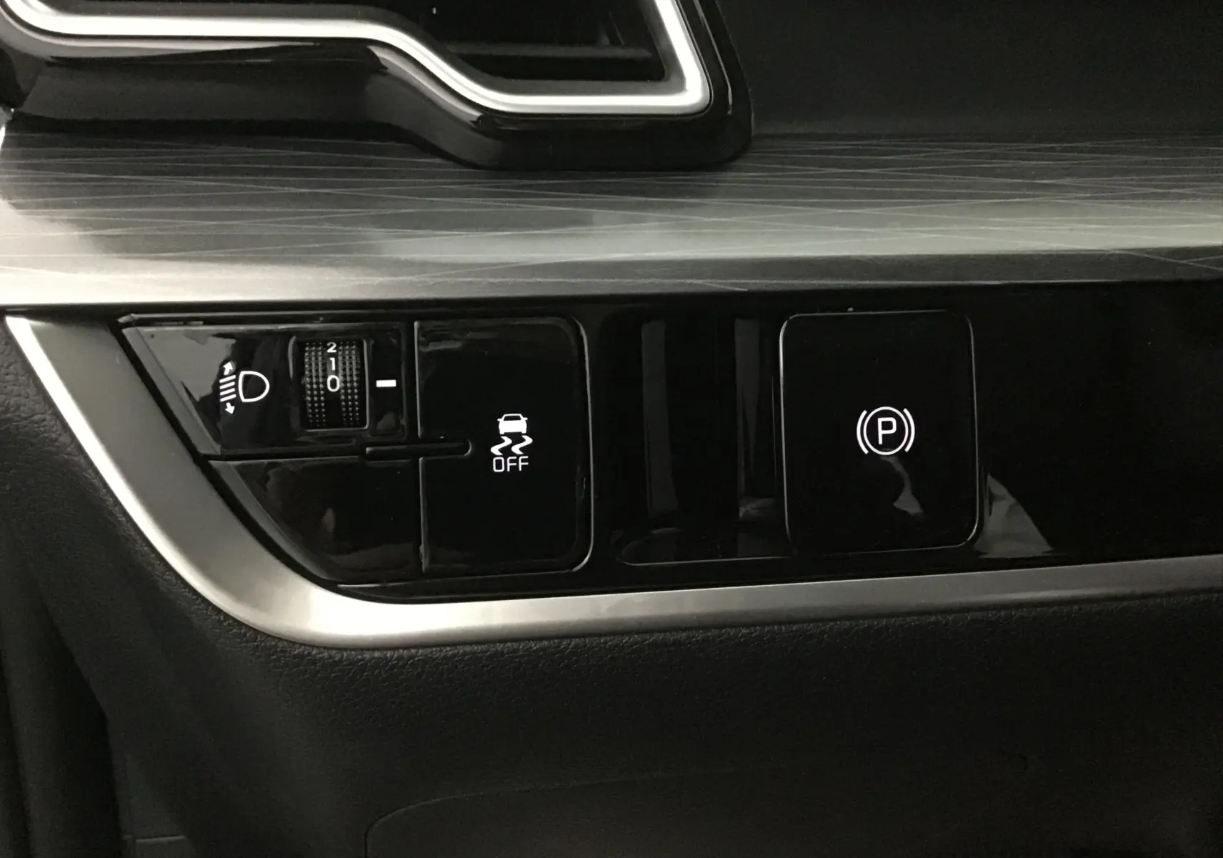 Gros plan sur les commandes de l'assistance à la conduite et frein de stationnement du Kia Sportage 2025 intérieur noir.