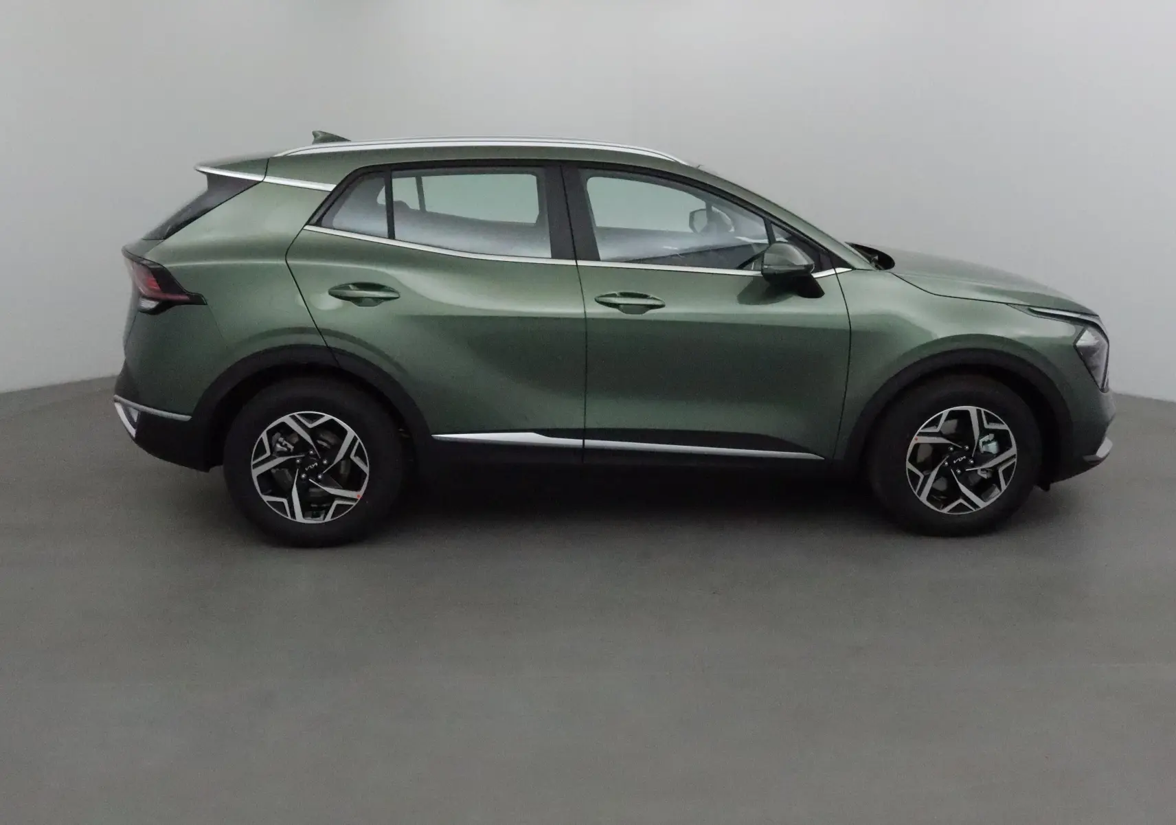 Vue profil côté gauche du SUV KIA SPORTAGE 2025 vert Borneo avec jantes alliage et lignes sculptées modernes.