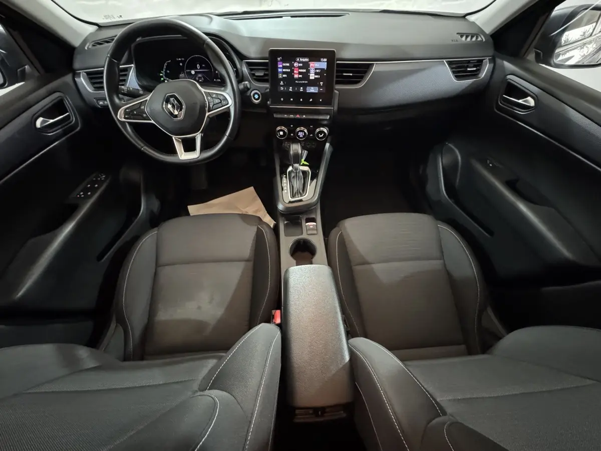 Vue intérieure avant de la Renault Arkana Business E-TECH 145, tableau de bord noir avec écran tactile central et volant multifonctions.