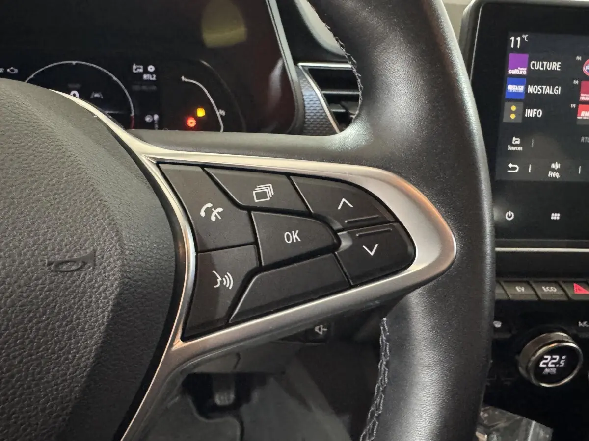Gros plan sur les commandes au volant en cuir noir du Renault Arkana Business E-TECH 145, avec écran tactile visible à droite.