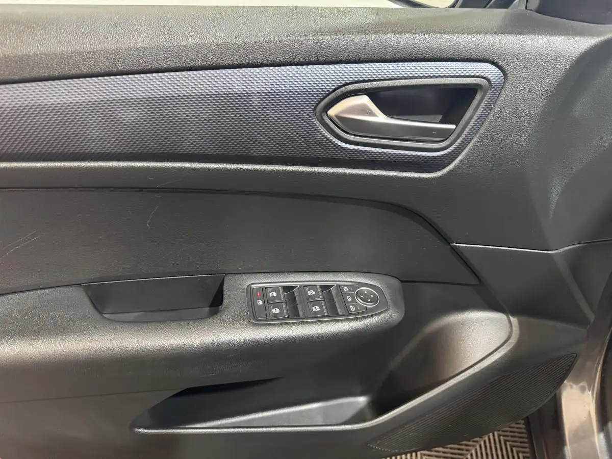 Vue intérieure côté gauche de la porte Renault Arkana Business E-TECH 145 avec commandes de vitres et poignée argentée.