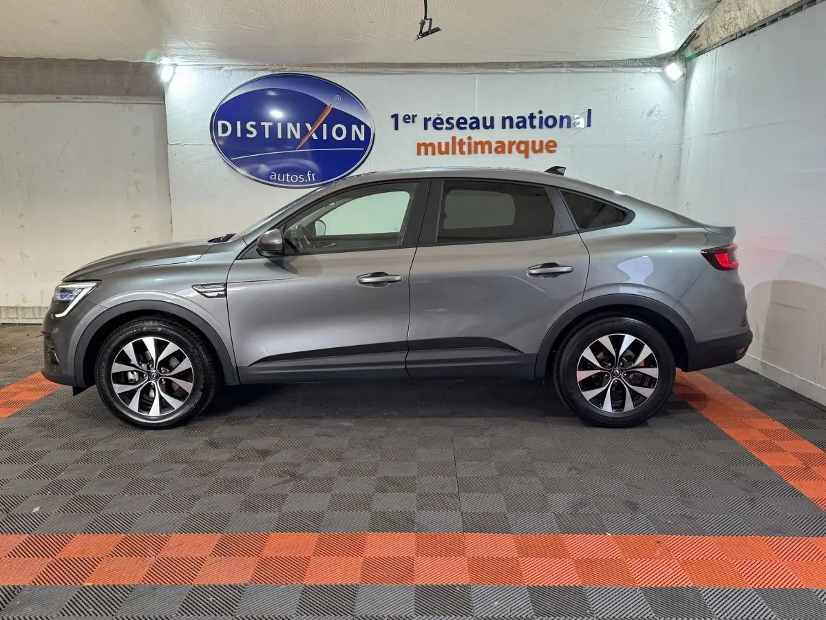 Renault Arkana Business E-TECH 145 gris foncé vue de profil côté gauche, en intérieur sur sol damier noir et orange.