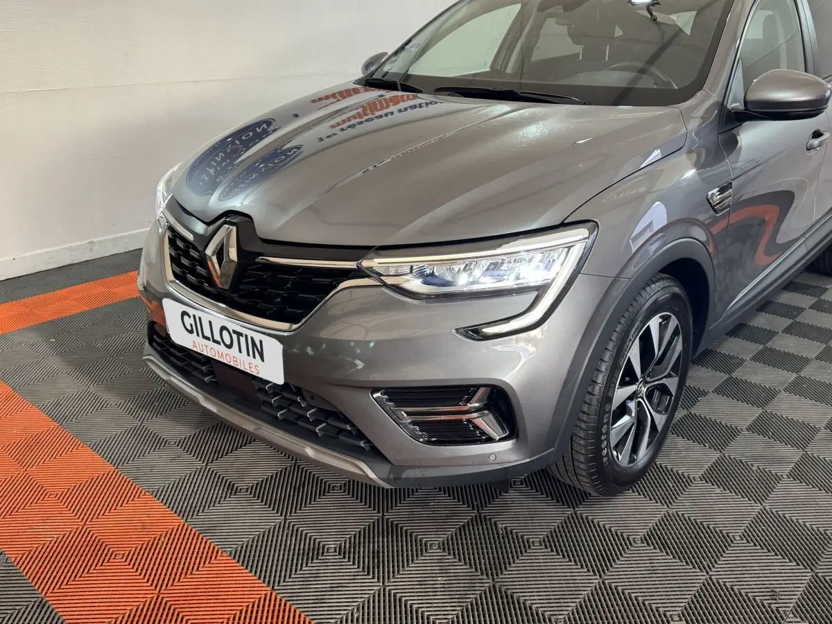 Vue 3/4 avant droit d'une Renault Arkana Business E-TECH 145 gris foncé avec phares LED et jantes alliage.