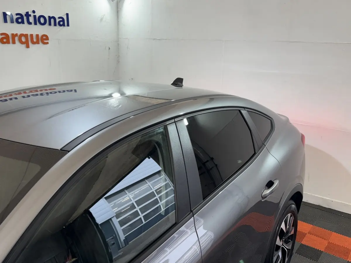 Vue 3/4 arrière du côté gauche d'une Renault Arkana Business E-TECH 145 gris foncé avec vitres teintées et jantes alliage.