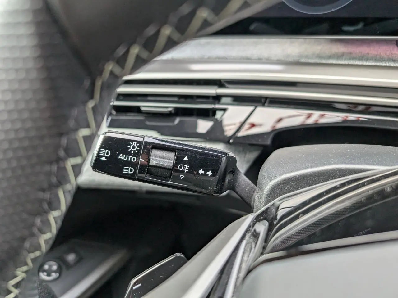 Gros plan sur la commande des feux et clignotants à gauche du volant du Peugeot 3008 GT bleu métallisé 2025.