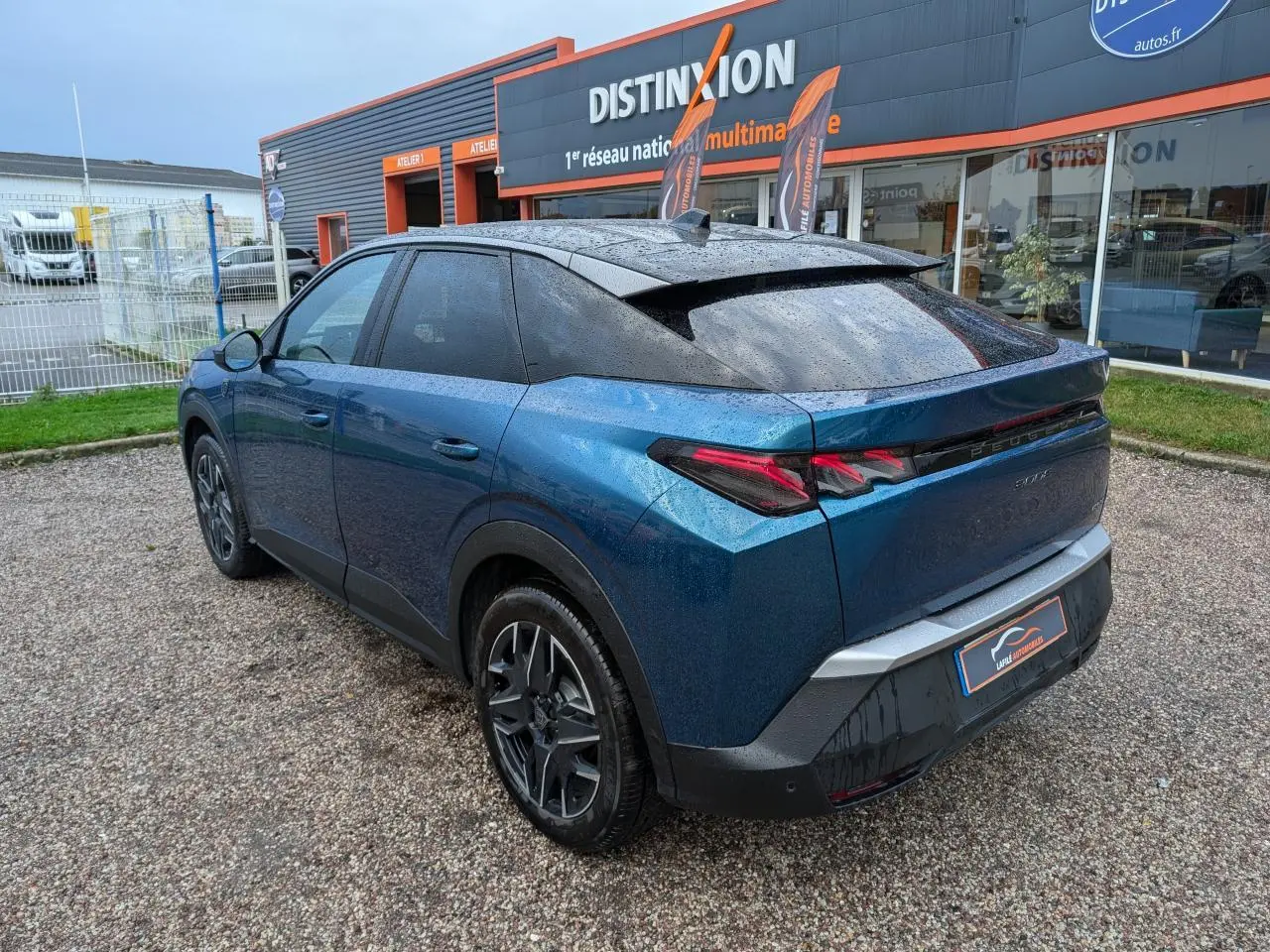 Vue 3/4 arrière droite du Peugeot 3008 GT hybride bleu métallisé avec toit noir et feux arrière à griffes LED.