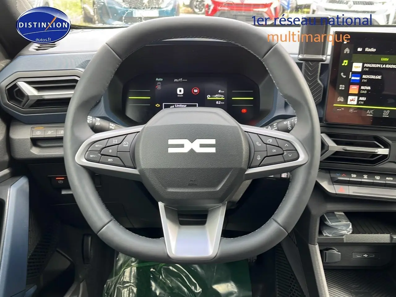 Vue intérieure centrée sur le volant multifonction du Dacia Duster gris schiste 2025 avec tableau de bord numérique et écran tactile.