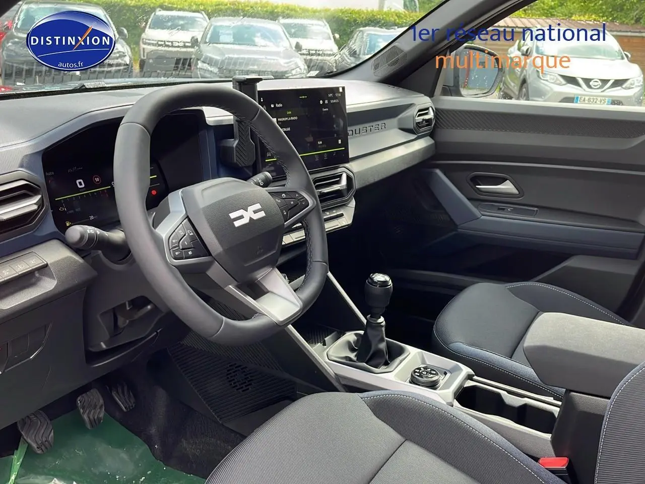 Intérieur avant du Dacia Duster 2025 gris schiste, volant multifonction et boîte manuelle visibles côté conducteur.