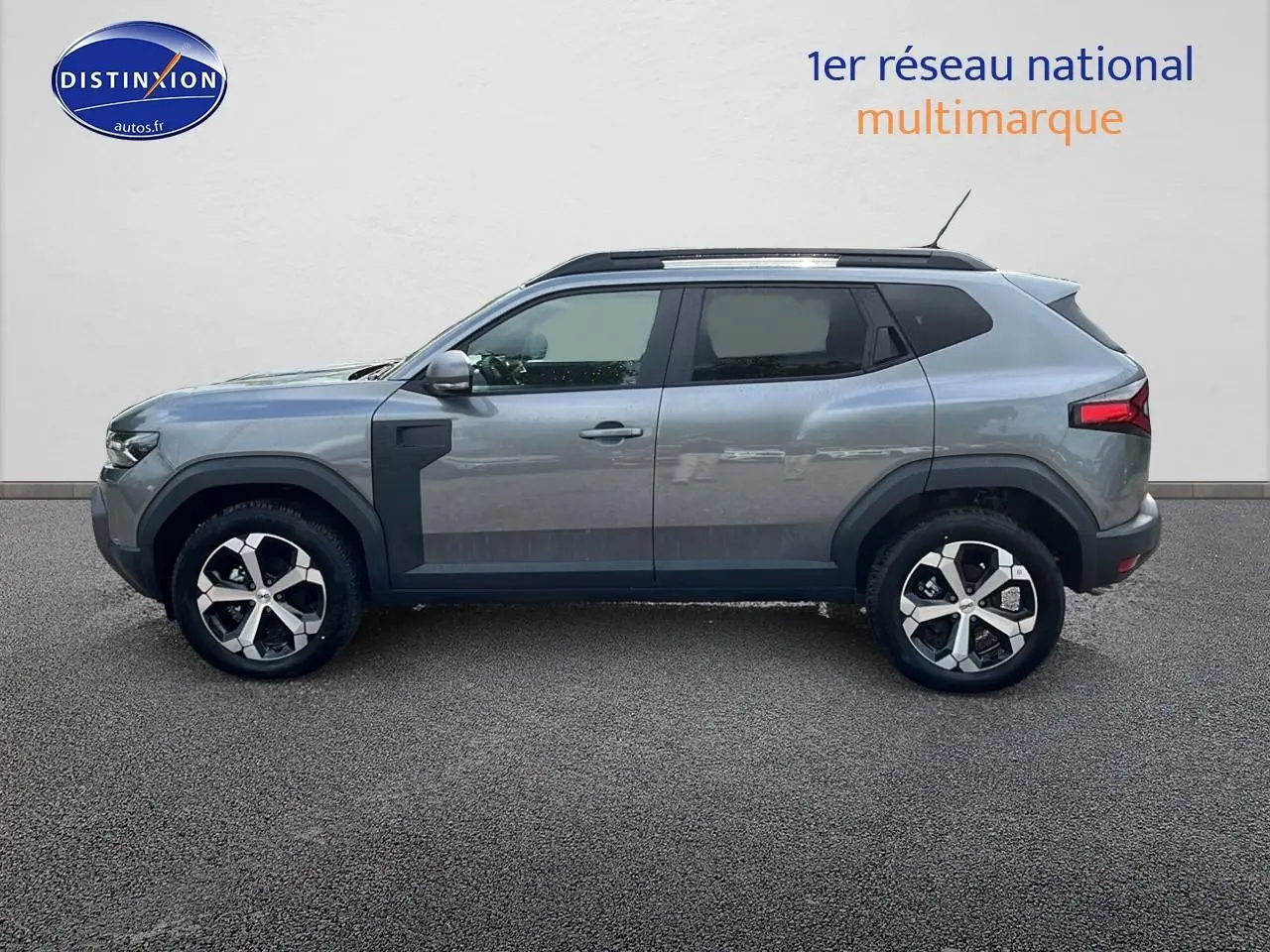 Profil droit du Dacia Duster 2025 gris schiste avec jantes alliage et barres de toit noires visibles.