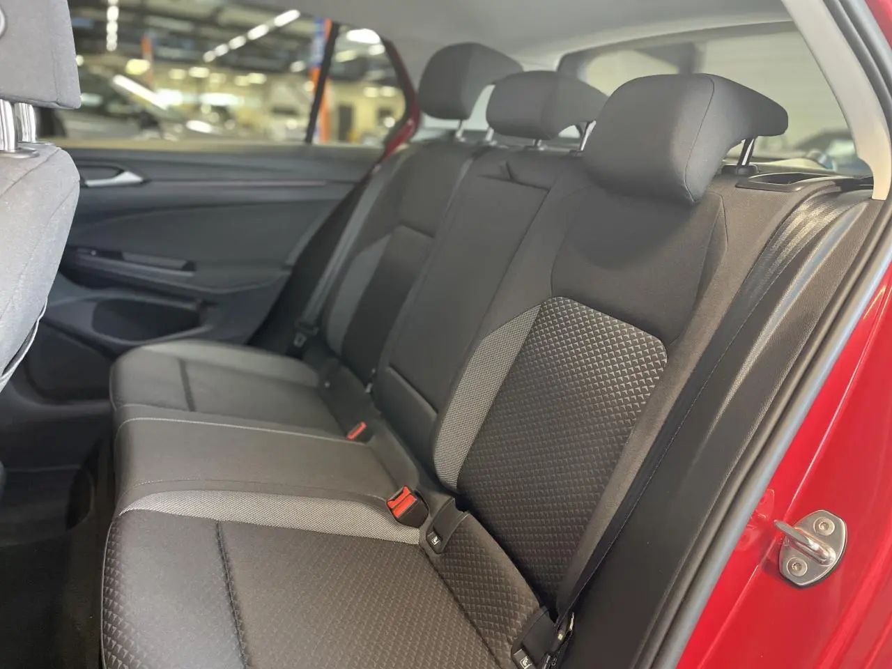 Vue intérieure côté droit sur la banquette arrière noire de la Volkswagen Golf rouge métallisée, avec ceintures visibles.