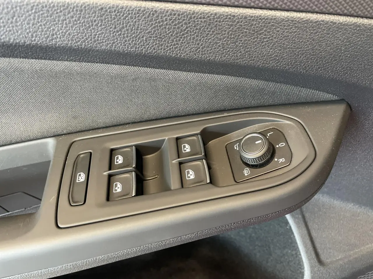 Panneau de commande des vitres et rétroviseurs côté gauche intérieur d'une Volkswagen Golf rouge métallisée 2022.