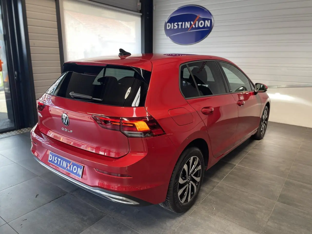 Volkswagen Golf rouge métallisé vue 3/4 arrière droit en intérieur avec jantes alliage distinctives