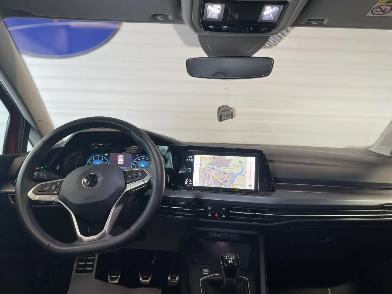 Vue frontale intérieure du tableau de bord et volant cuir noir de la Volkswagen Golf 1.5 TSI Active 2022 avec écran tactile et levier de vitesses manuel.