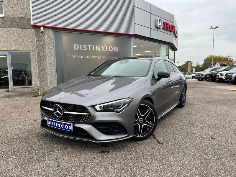 Mercedes Classe CLA Shooting Brake 250 AMG Line gris montagne métallisé vue 3/4 avant avec jantes AMG noires devant un concessionnaire