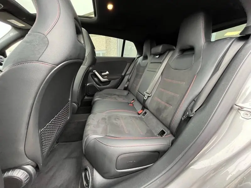 Vue latérale droite de l'intérieur arrière d'une Mercedes CLA Shooting Brake 250 AMG Line, sièges noirs avec surpiqûres rouges.