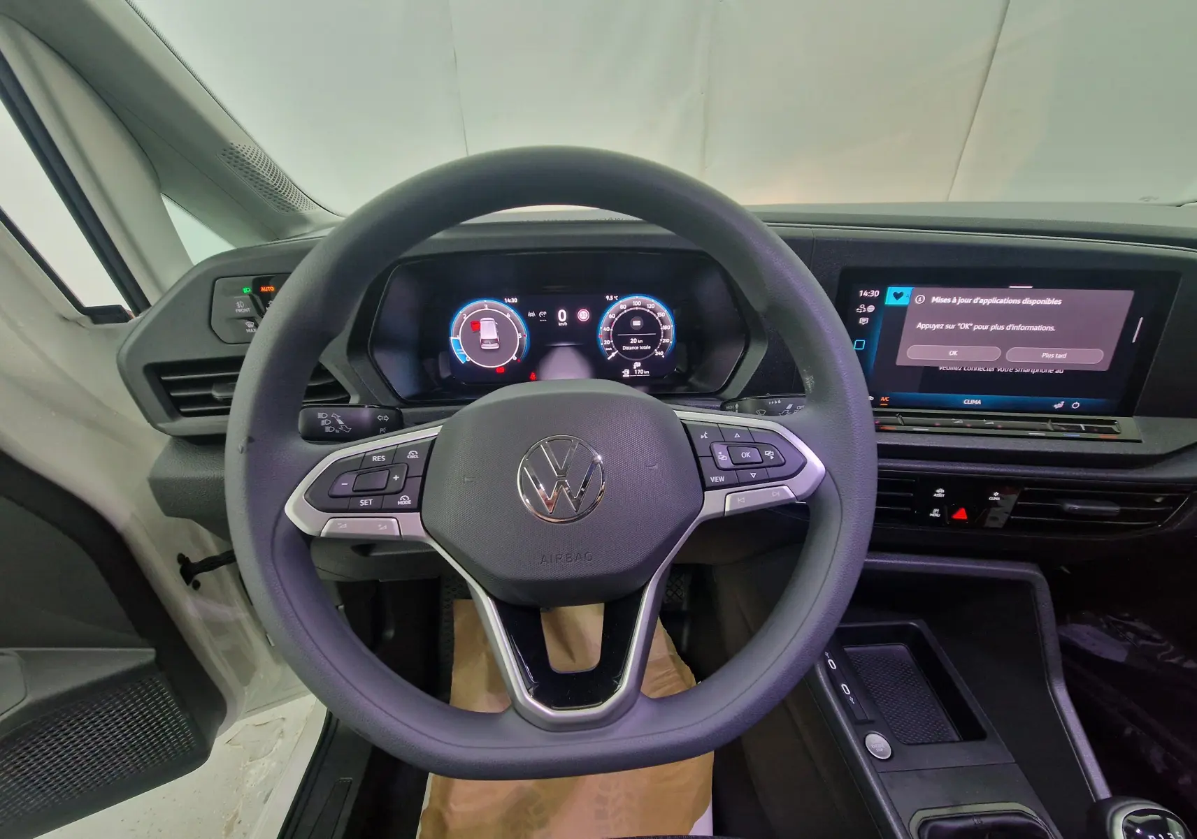 Vue centrée sur le volant et le tableau de bord numérique du Volkswagen Caddy Maxi blanc, intérieur moderne et connecté.