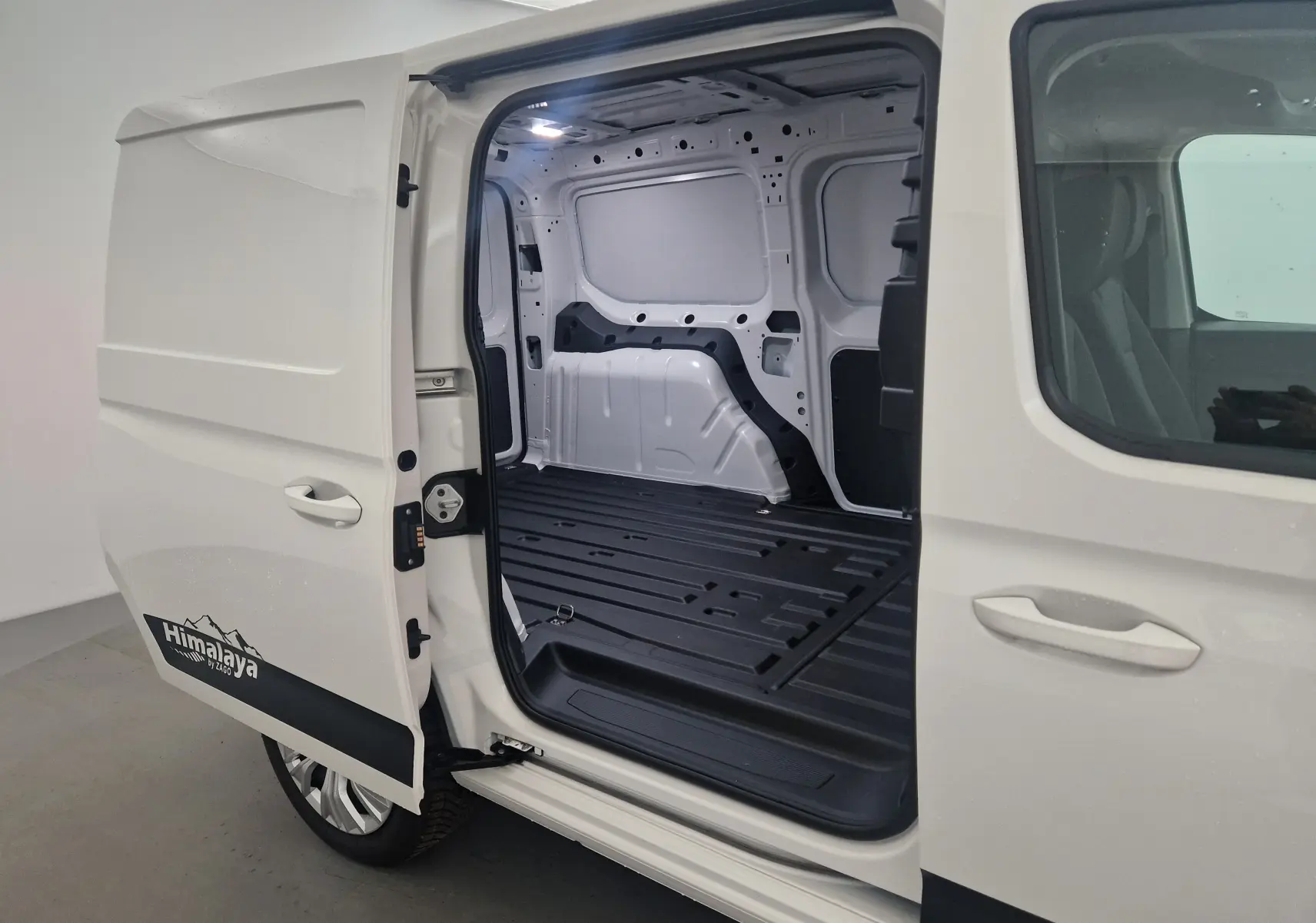 Vue latérale gauche du Volkswagen Caddy Maxi blanc version Himalaya avec porte coulissante ouverte montrant l'intérieur utilitaire vide.