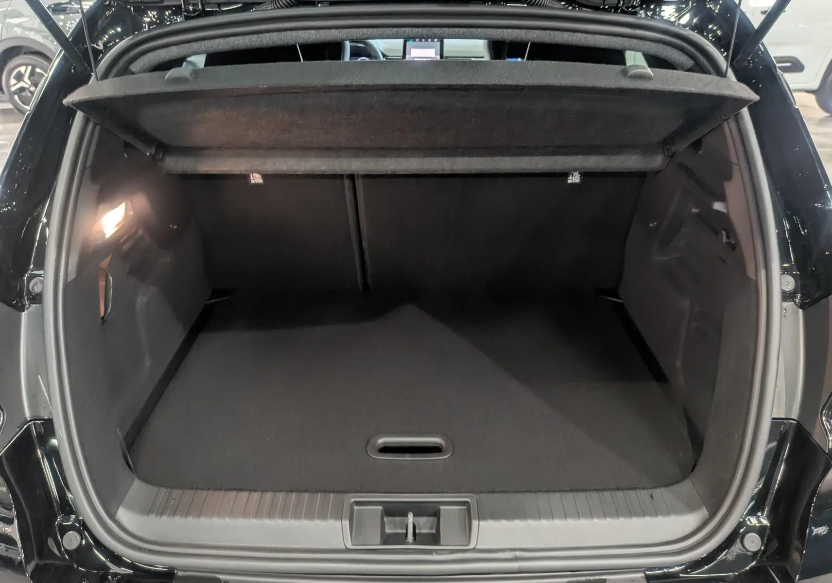 Coffre ouvert vu de l'arrière du Renault Captur E-TECH Full Hybrid noir étoilé, montrant un espace de chargement vide et éclairé.