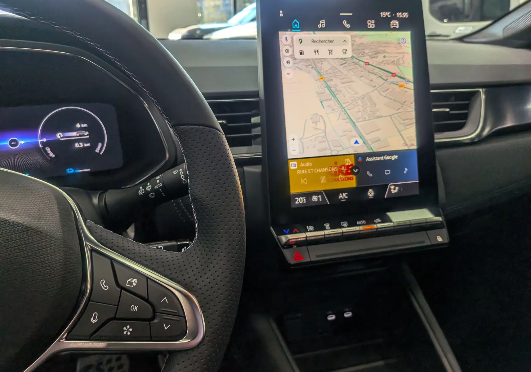 Vue rapprochée de l'intérieur du Renault Captur E-Tech 2025, montrant le volant et l'écran tactile central avec navigation active.