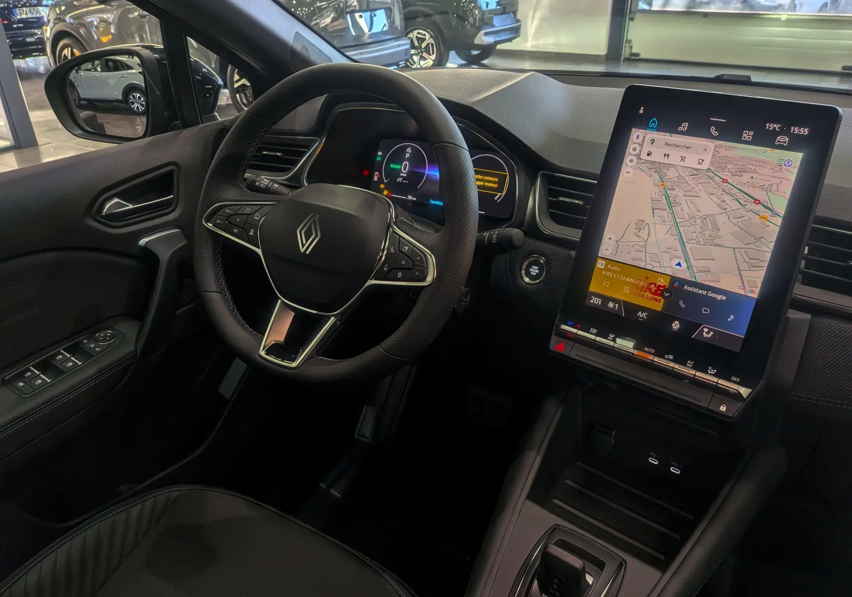 Intérieur noir du Renault Captur E-TECH 2025, vue du poste de conduite avec volant et grand écran tactile central.