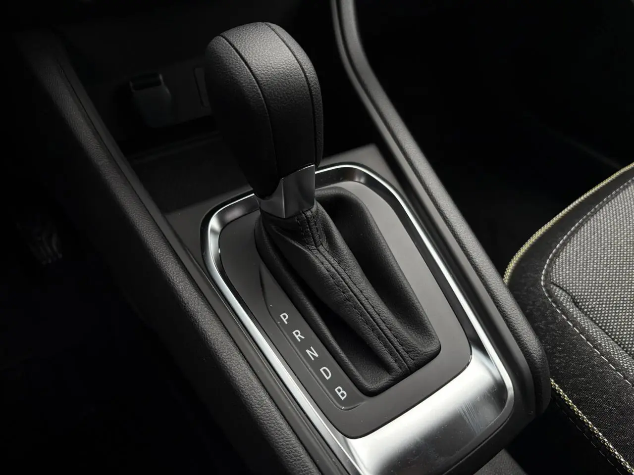 Gros plan sur le levier de vitesses automatique noir du Renault Captur 2025, avec coutures apparentes et console sombre.