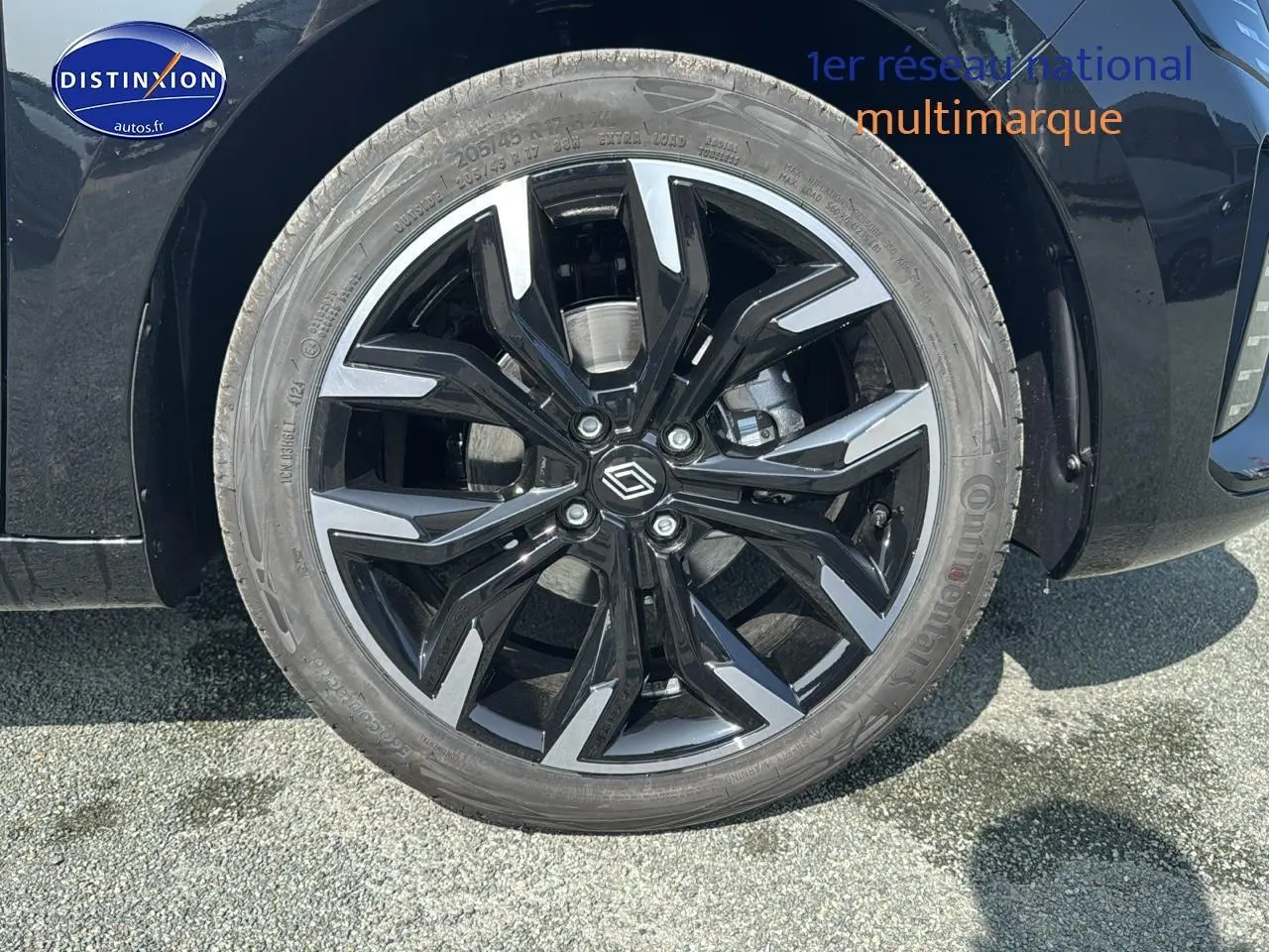 Gros plan sur la jante alu noire et argentée côté gauche d'une Renault Clio V noire, avec logo central distinctif.