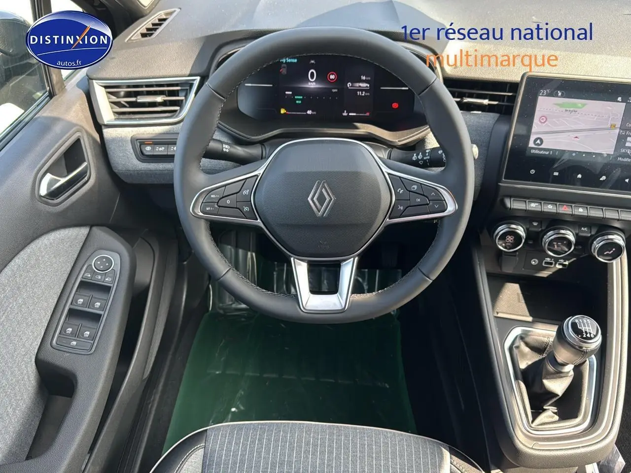 Vue intérieure frontale du poste de conduite de la Renault Clio V avec volant multifonction et écran tactile central.