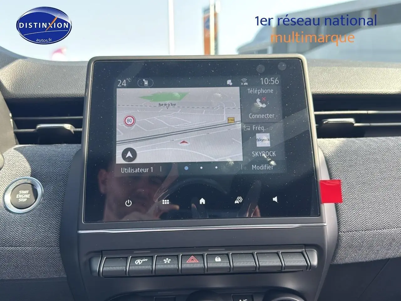 Vue intérieure centrée sur l'écran tactile du tableau de bord de la Renault Clio V noire, avec bouton start engine visible à gauche.