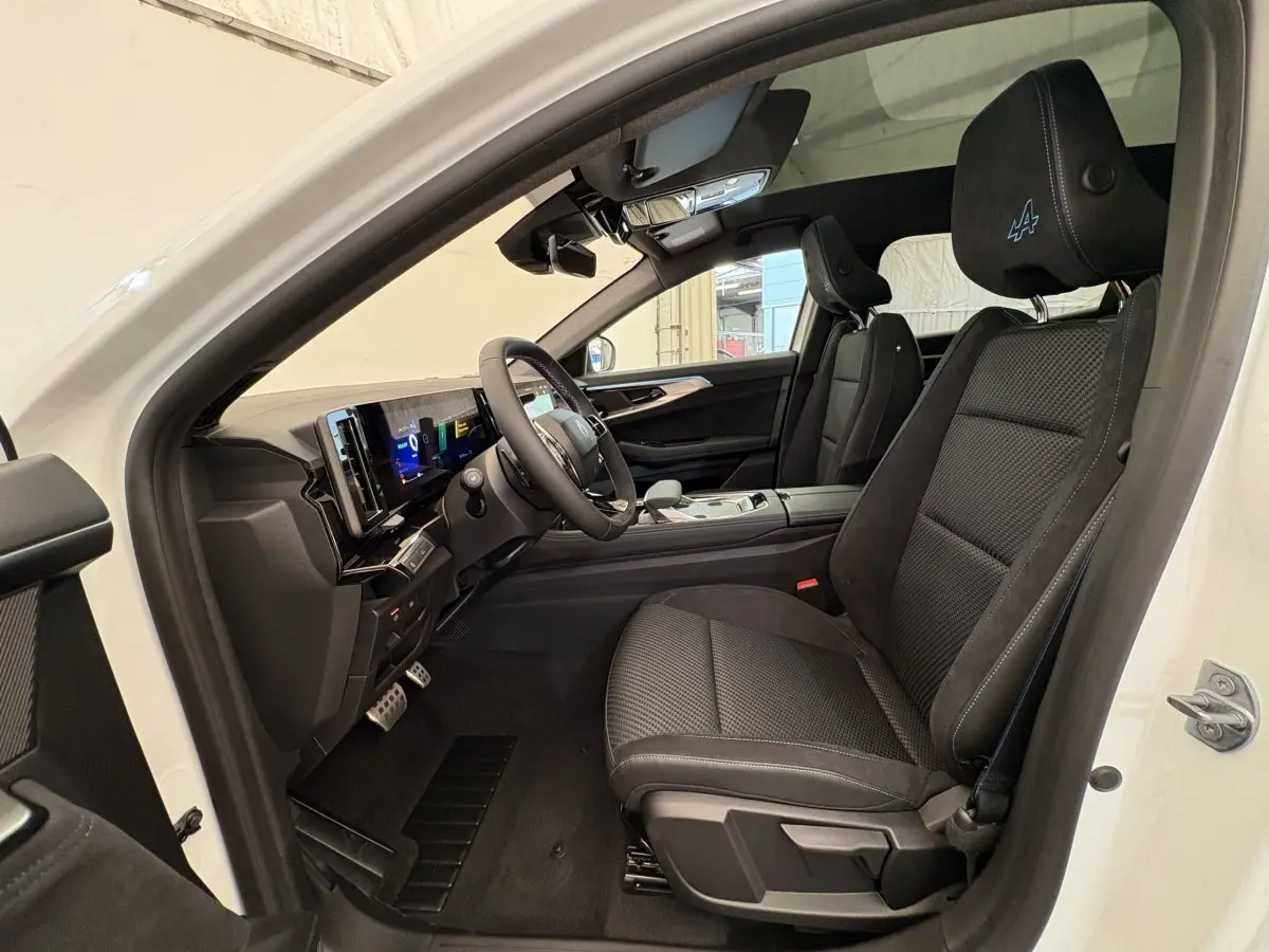 Vue intérieure côté conducteur du Renault Espace blanc 2025, sièges noirs avec logo Alpine brodé sur appuie-tête.