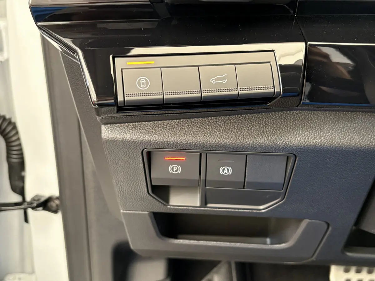 Gros plan sur les commandes de verrouillage et ouverture du coffre du Renault Espace blanc, côté conducteur.