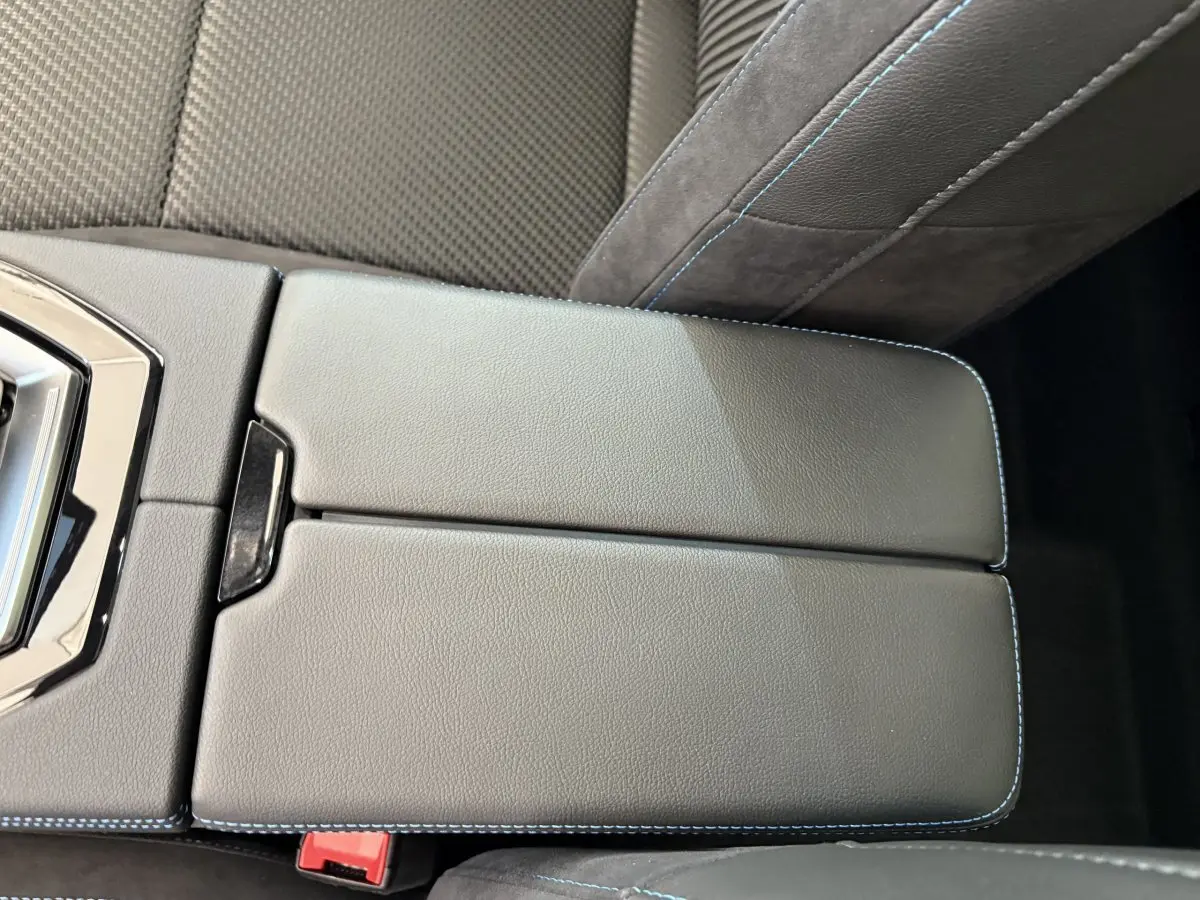 Gros plan sur l'accoudoir central en cuir noir avec surpiqûres bleues dans l'habitacle du Renault Espace blanc.