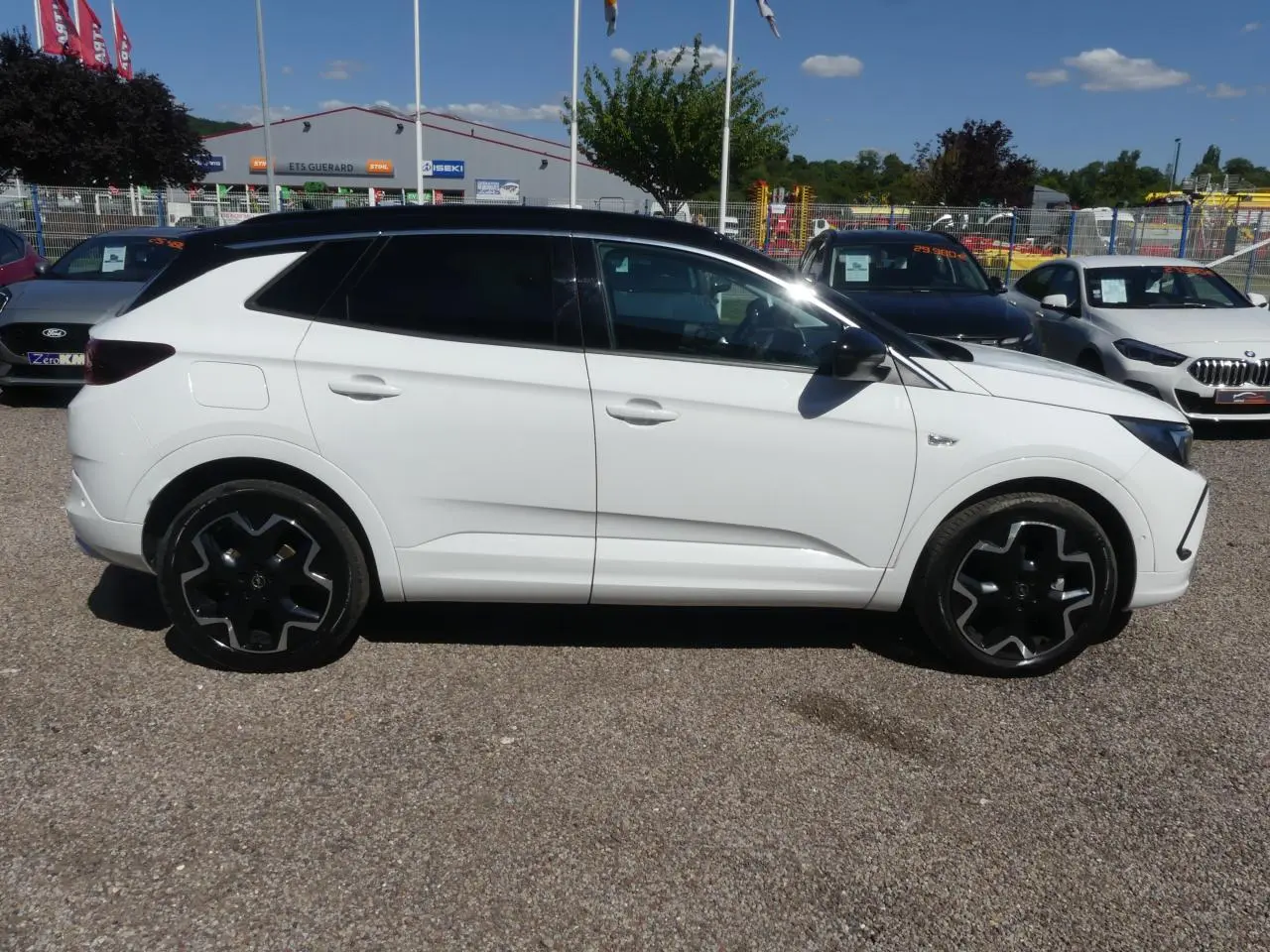 Opel Grandland blanc métallisé vu de profil côté gauche avec toit noir et jantes alliage noires.