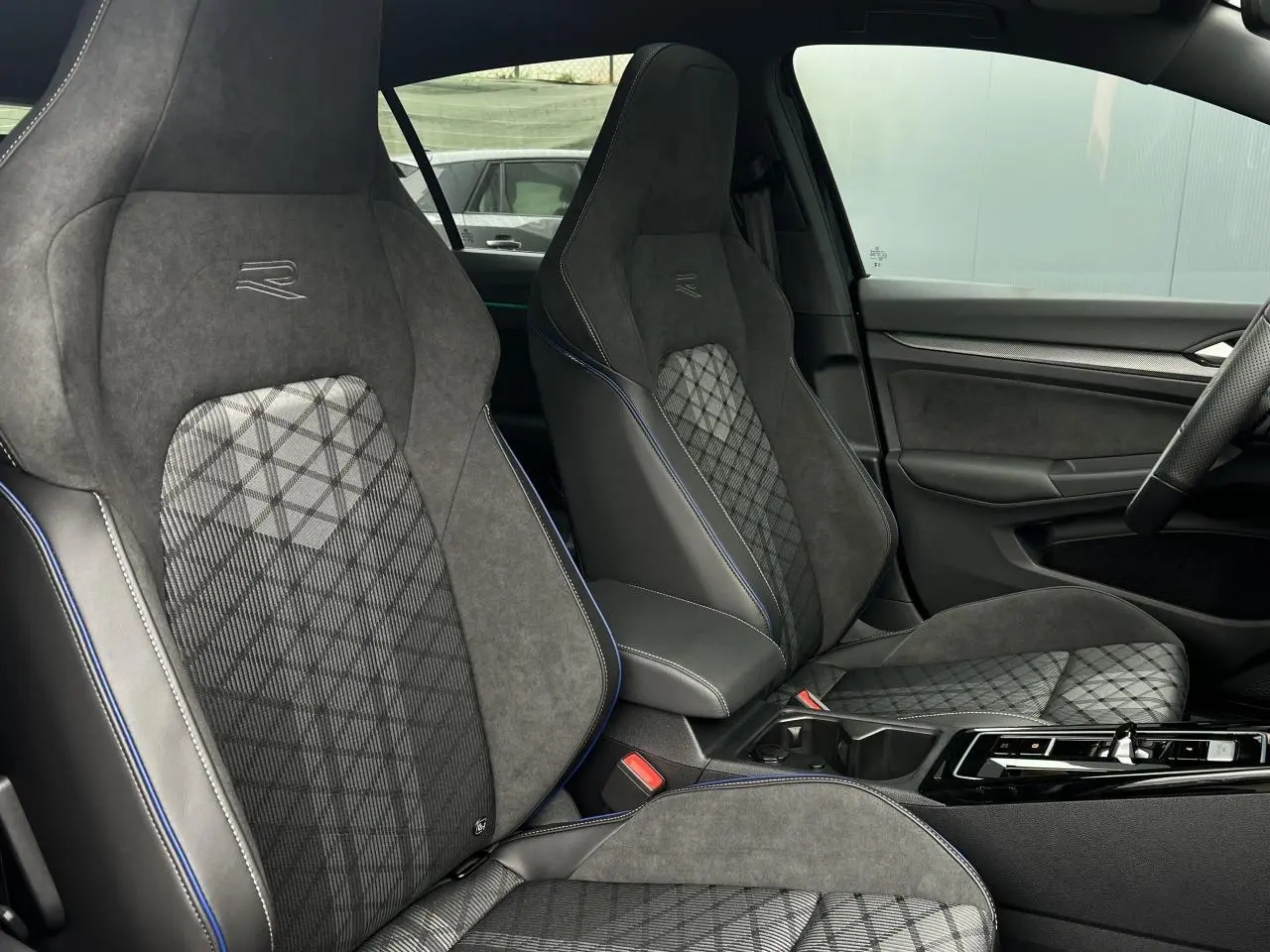Vue intérieure côté droit montrant les sièges sport R-Line en alcantara gris avec surpiqûres bleues et motifs géométriques.