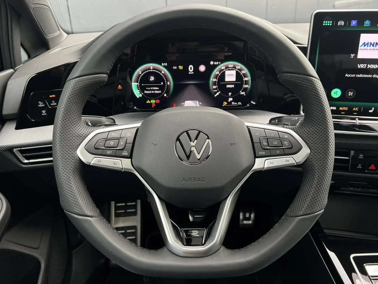 Vue intérieure centrée sur le volant cuir perforé noir avec logo VW et tableau de bord numérique de la Volkswagen Golf VIII R-Line.