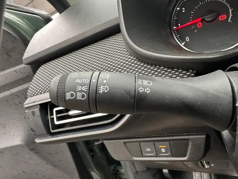Gros plan sur la commande des feux et clignotants du Dacia Jogger 2025, intérieur avec détails noirs et tissu gris.