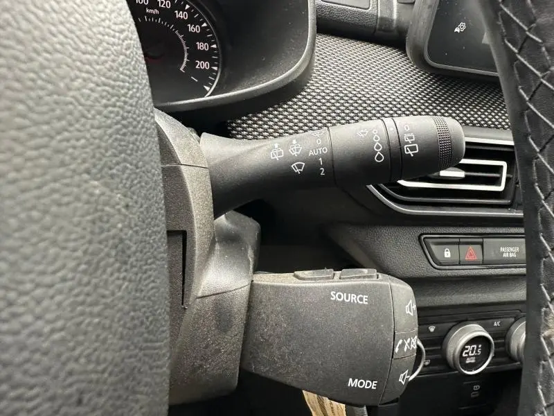 Détail intérieur du volant côté gauche du Dacia Jogger 2025, montrant les commandes de phares et audio sur fond noir.