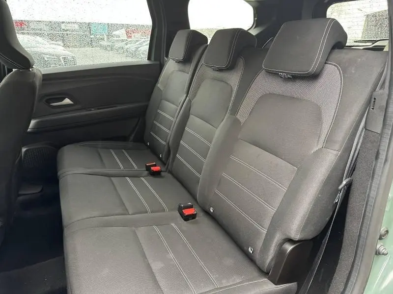 Vue latérale intérieure sur la banquette arrière noire du Dacia Jogger 2025 en Kaki Lichen, version 7 places.
