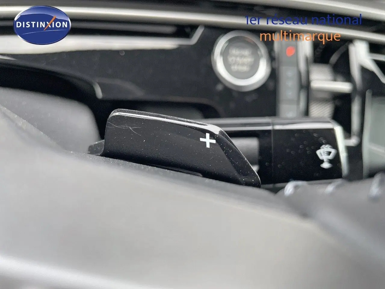 Gros plan sur la palette de changement de vitesse "+" du Peugeot 3008 Hybrid 2025, intérieur noir avec bouton start visible.