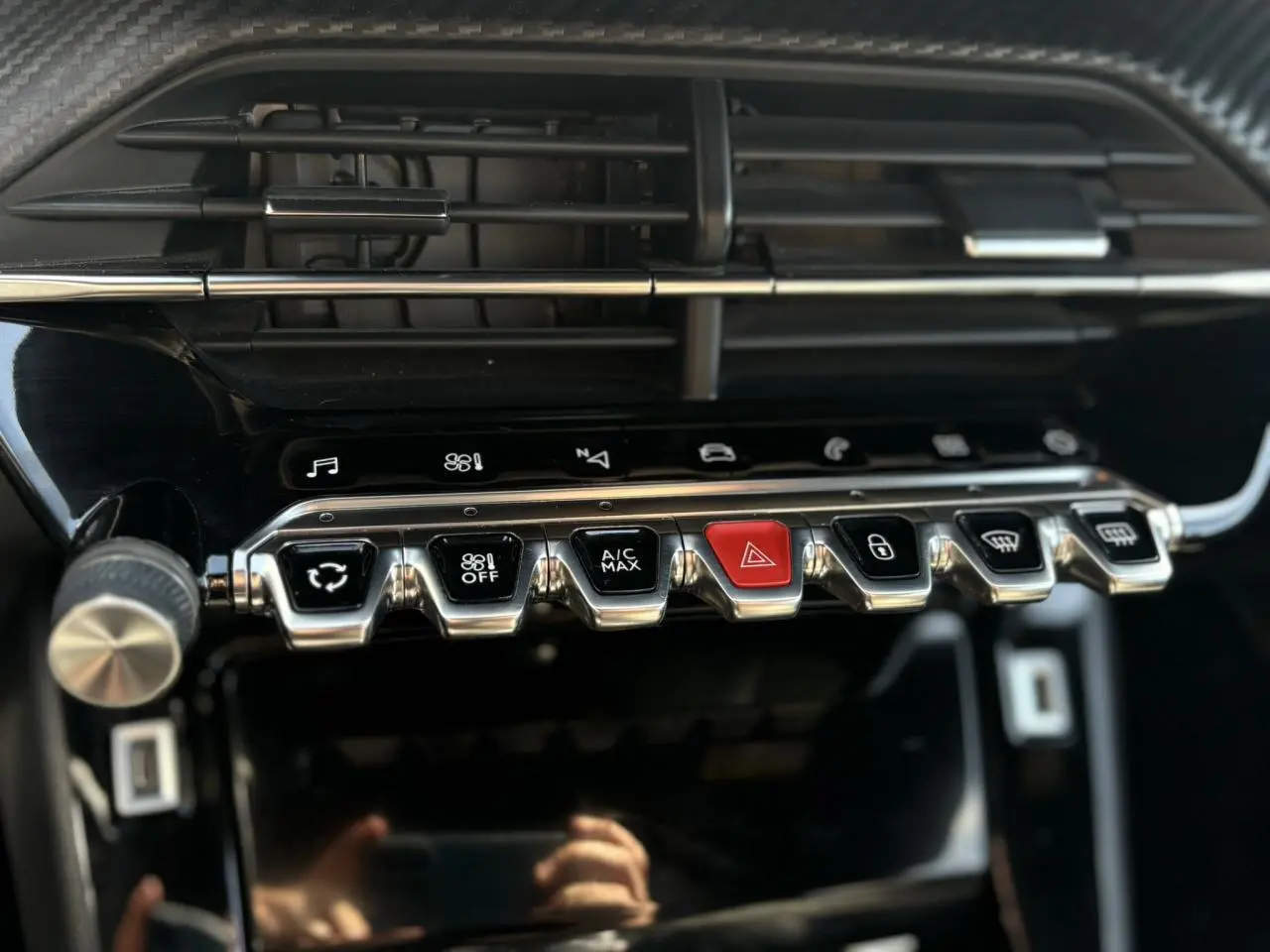 Gros plan sur la console centrale noire du Peugeot 2008 2021 GT avec rangée de boutons chromés et bouton rouge d’alerte.