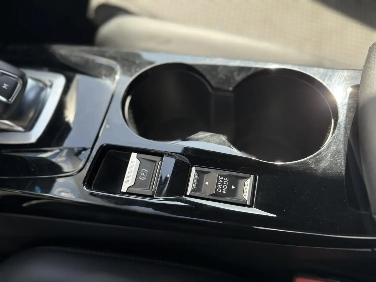 Gros plan sur la console centrale noire brillante du Peugeot 2008 GT 2021 avec boutons frein électrique et mode de conduite.