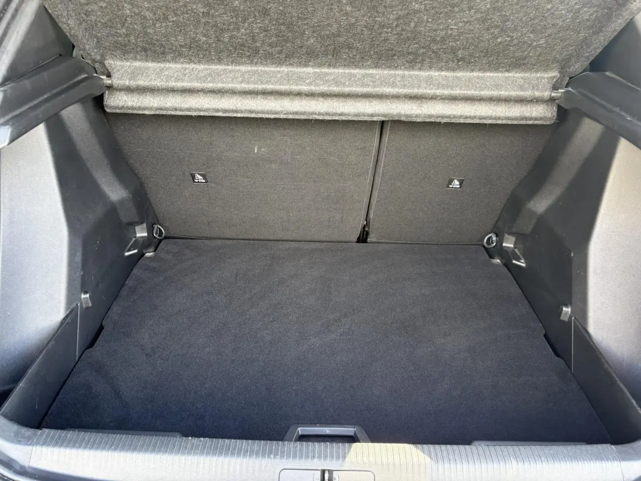 Coffre ouvert d'un Peugeot 2008 noir Onyx, montrant l'espace de chargement propre et la doublure intérieure grise.