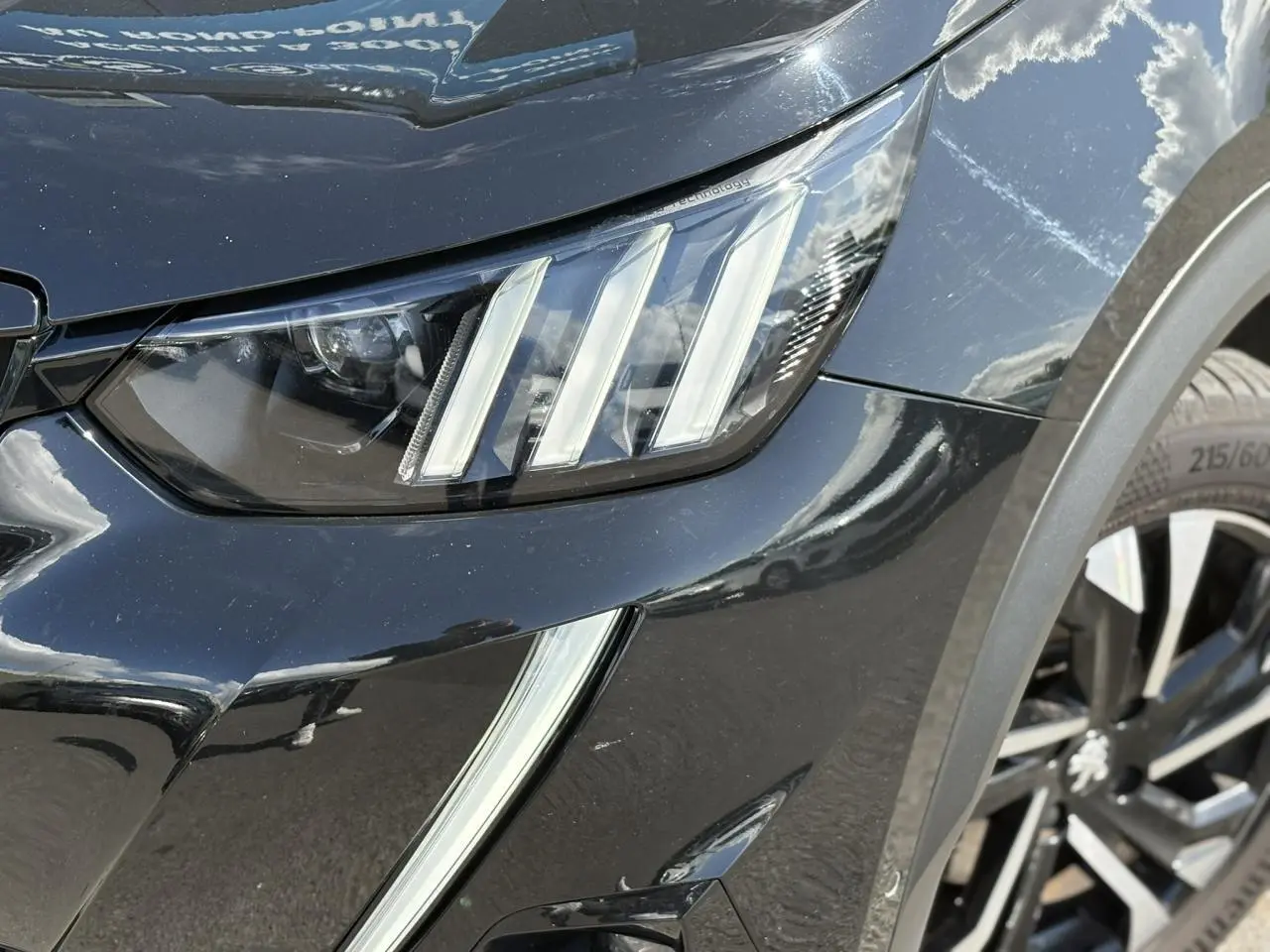 Gros plan sur le phare avant gauche et jante alliage bi-ton du Peugeot 2008 noir Onyx finition GT.