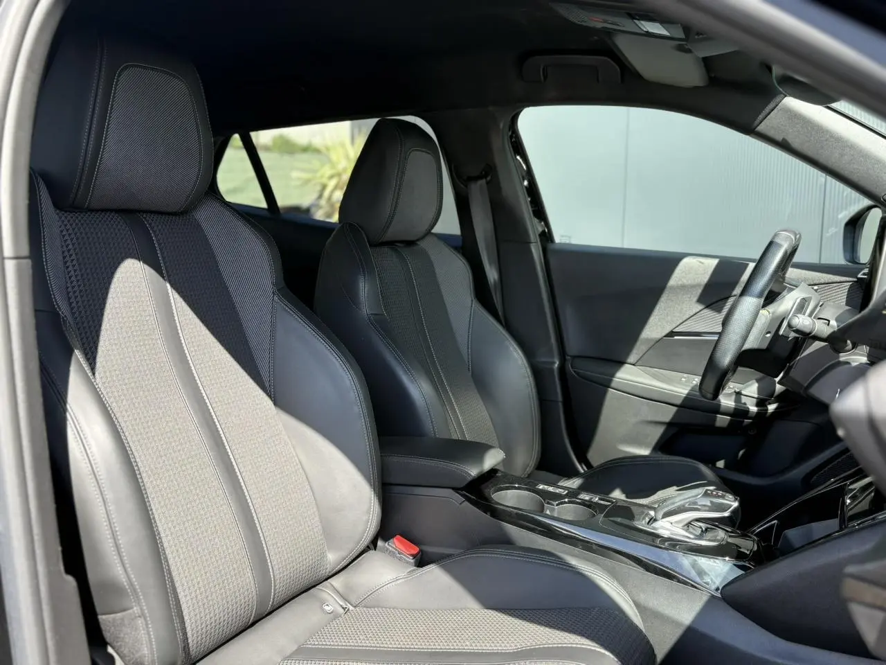 Intérieur avant du Peugeot 2008 GT 2021 en tissu et TEP noir avec console centrale et volant compact cuir.