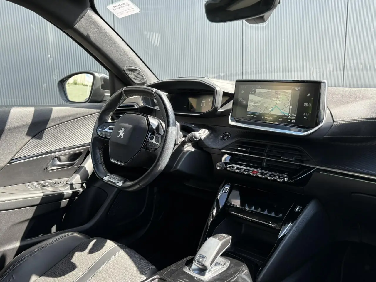 Intérieur avant gauche du Peugeot 2008 noir Onyx 2021, tableau de bord avec écran GPS tactile et volant compact cuir.