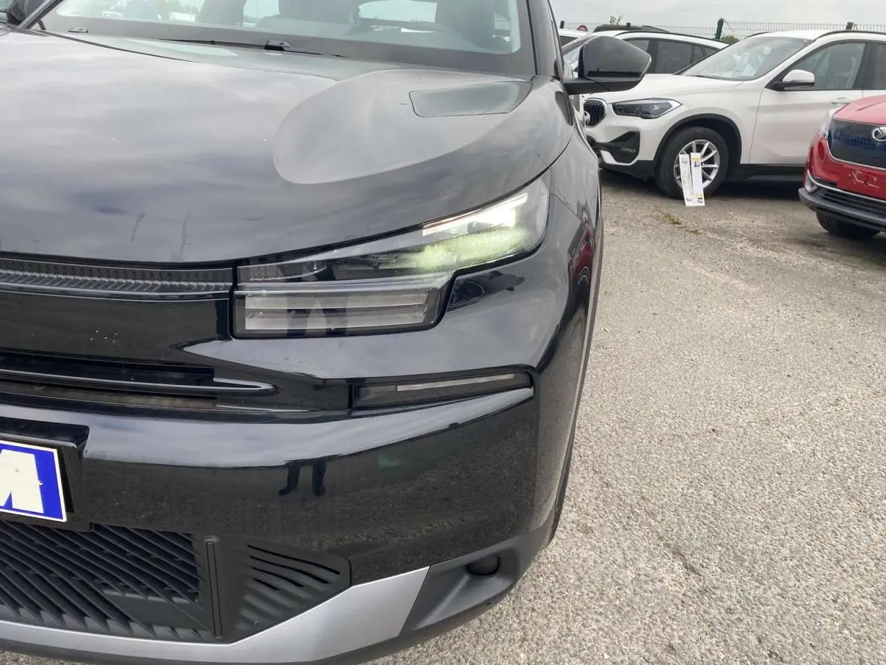 Gros plan sur l'avant droit de la Citroën C4 noire Perla Nera avec ses phares LED allumés et calandre moderne.