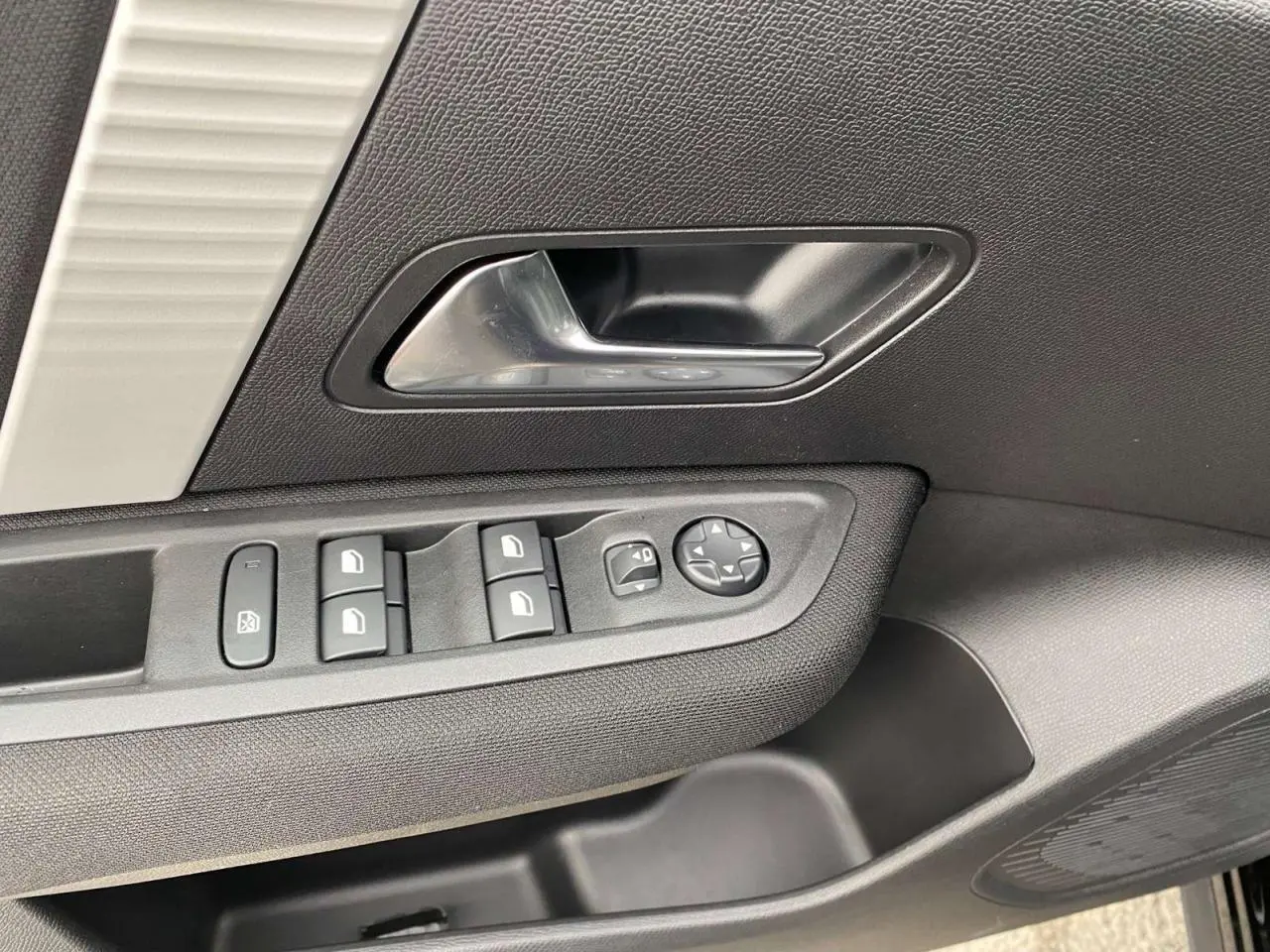 Gros plan sur la poignée intérieure et les commandes des vitres côté conducteur de la Citroën C4 noire Perla Nera.