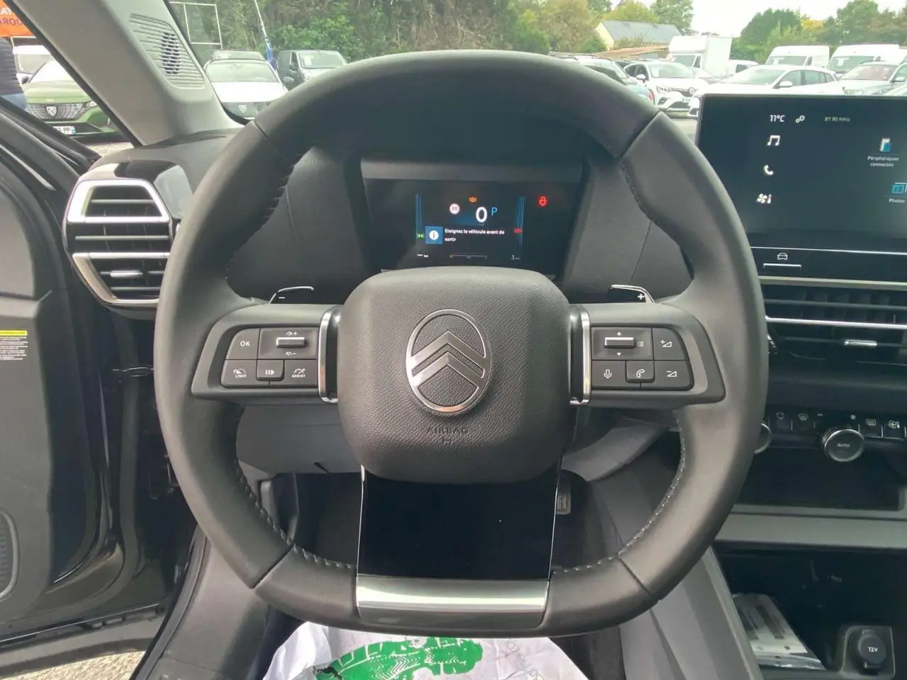 Vue centrée sur le volant noir du Citroën C4 hybride 2025, avec tableau de bord numérique et écran tactile visible.