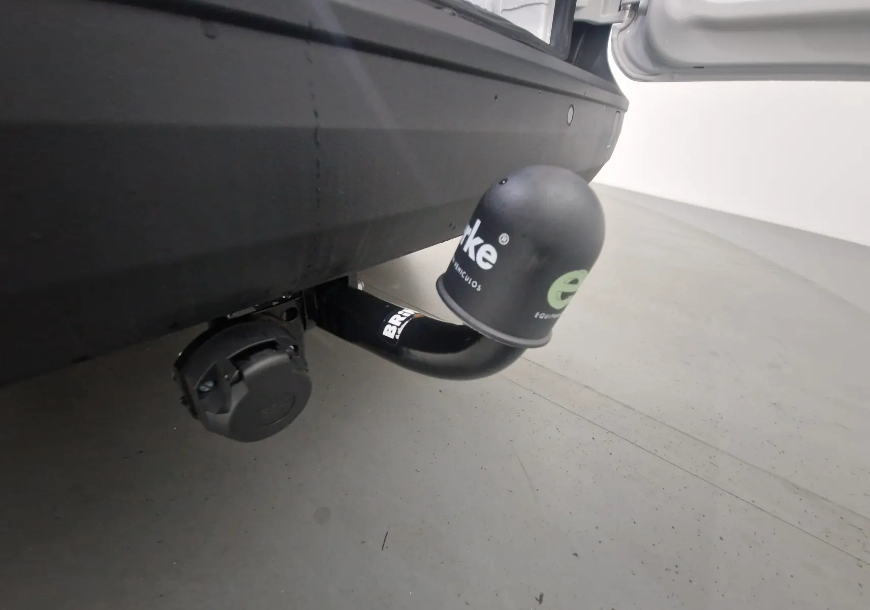 Gros plan sur l'attelage noir avec cache de protection sur le pare-chocs arrière noir d'un Volkswagen Caddy Maxi blanc.