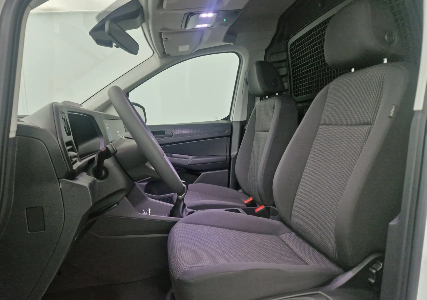 Vue arrière ouverte du Volkswagen Caddy Maxi blanc montrant l'espace de chargement vide avec roue de secours fixée à droite.